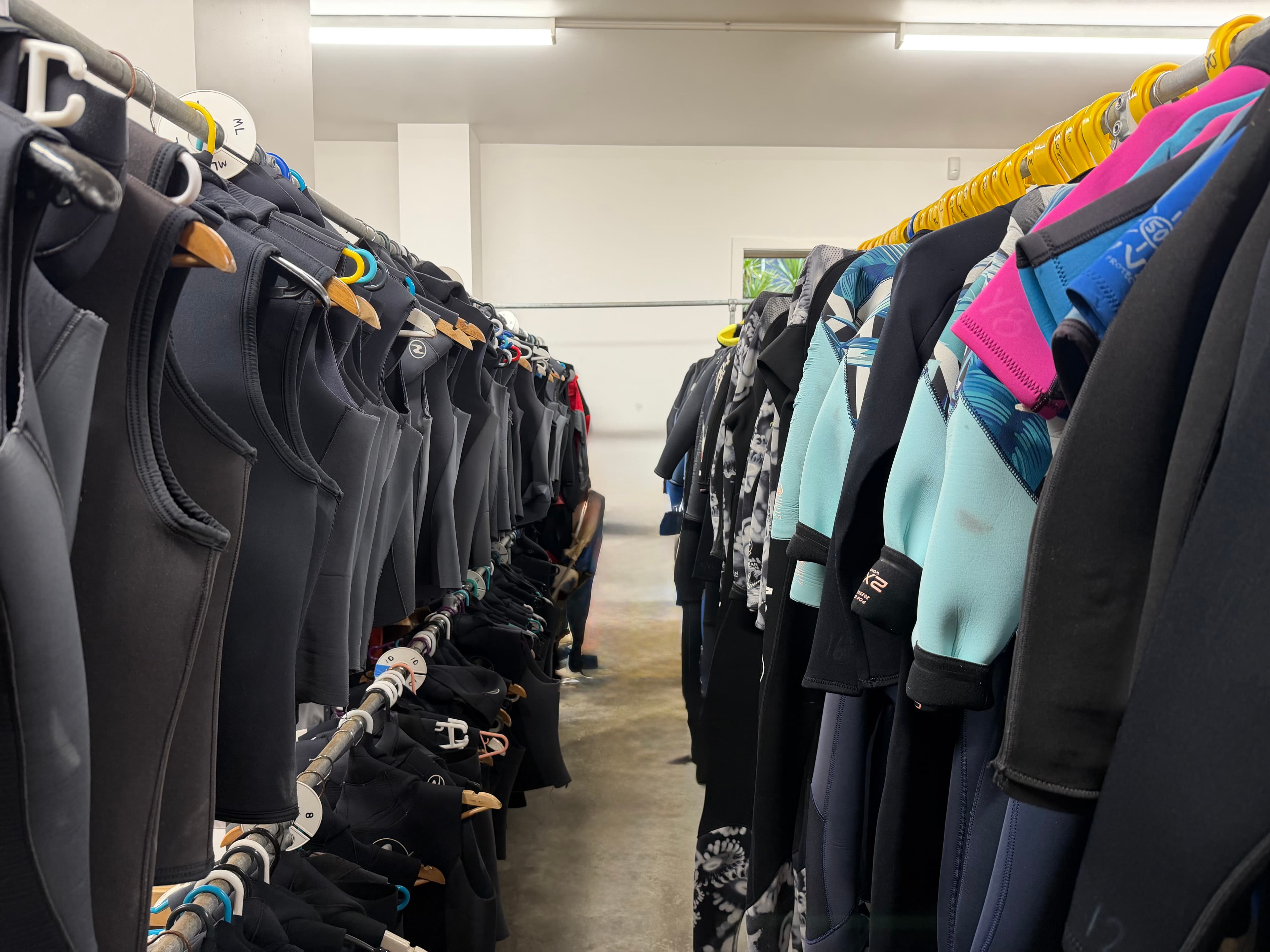 Racks of wetsuits in a dive shop gear shed